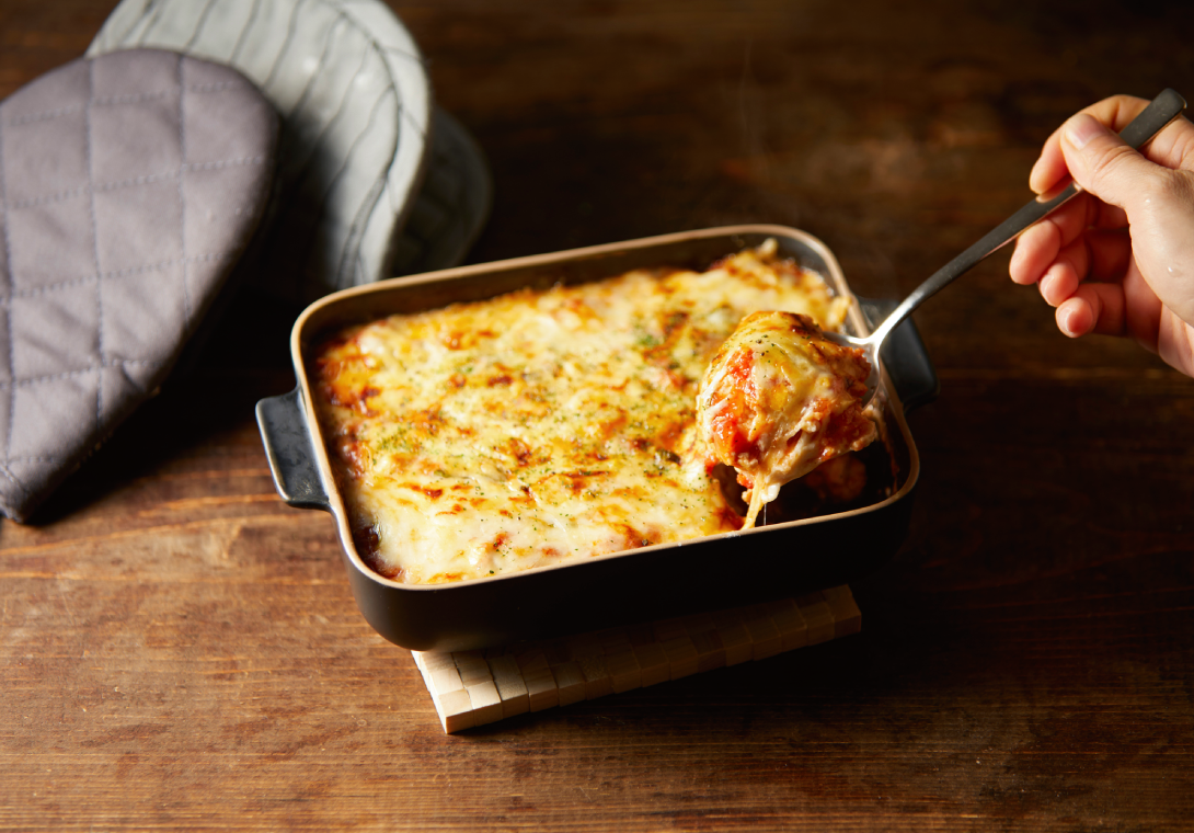 A baked cheesy lasagna being served with a spoon.