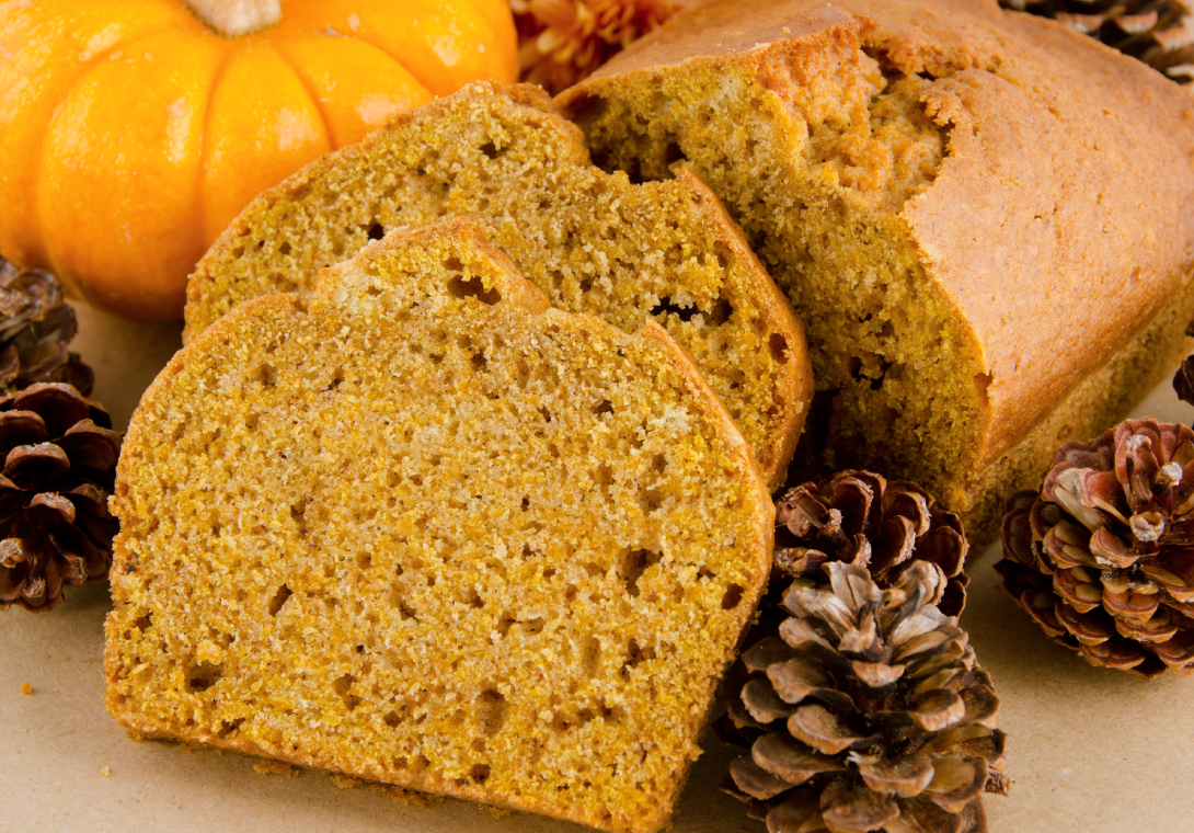 Slices of moist pumpkin bread with a pinecone beside them.